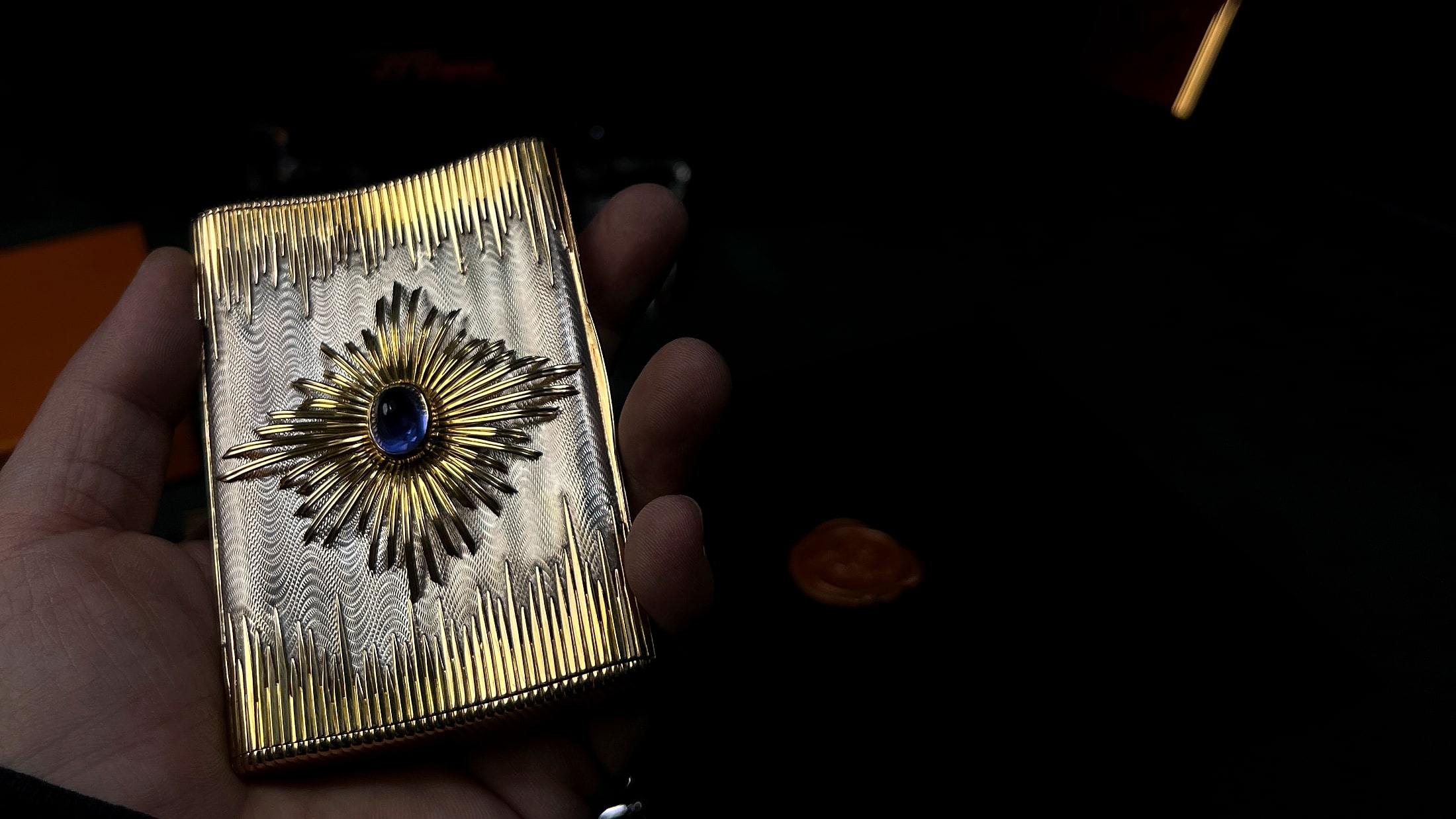 Gold starburst vintage lighter held for close inspection